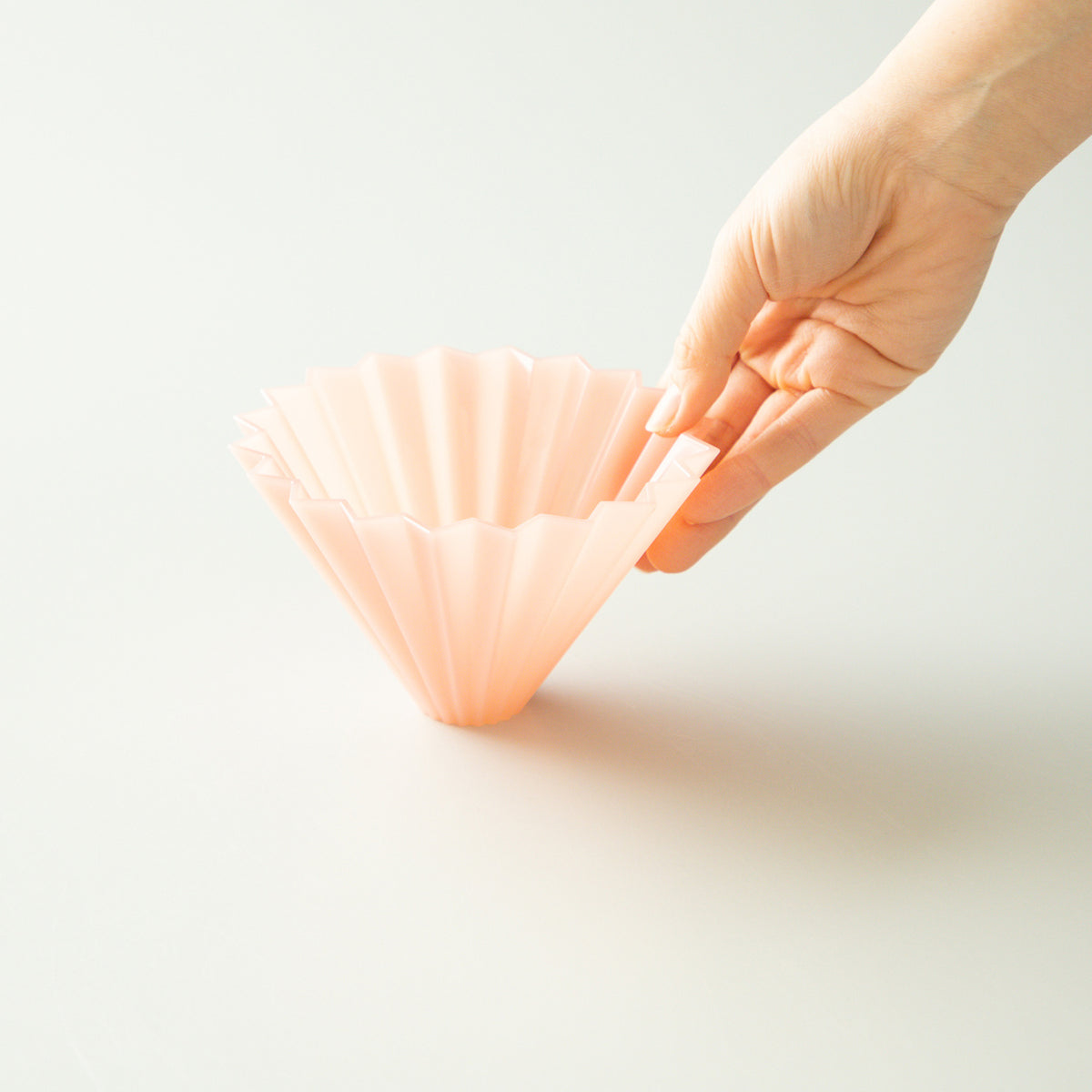 Pink Origami Air M plastic coffee dripper on a white background, showcasing its lightweight, modern design for pour-over brewing.